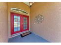 Close-up of a bright red, glass-paneled front door with decorative accents and a welcome mat at 1631 Madison Ave, North Port, FL 34286
