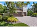 Elegant two-story home featuring a three-car garage, beautiful landscaping, and a brick driveway at 1719 Kenilworth St, Sarasota, FL 34231