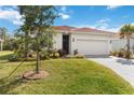 Charming home featuring a tile roof, well-kept lawn, and a paved driveway leading to the garage at 412 Daylily Blvd, Nokomis, FL 34275