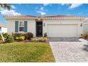 Single-story home featuring a well-kept lawn, paver driveway, and tidy landscaping at 412 Daylily Blvd, Nokomis, FL 34275