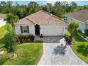 Beautiful single-story home with a red tile roof, manicured landscaping, and a paver driveway at 412 Daylily Blvd, Nokomis, FL 34275