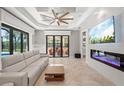 Cozy living room with a modern fireplace, tiled floors, and sliding glass doors overlooking the outdoor pool at 4668 Tuscana Dr, Sarasota, FL 34241