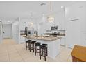 Bright, white kitchen featuring a center island with granite countertops and modern pendant lighting at 5554 Blue Azure Dr, Wimauma, FL 33598