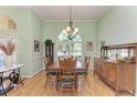 Formal dining room with elegant chandelier, hardwood floors, and large windows overlooking the yard at 5616 90Th Avenue E Cir, Parrish, FL 34219