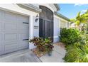 Close-up of a home's front entrance, featuring a gray garage door and lush landscaping at 5919 100Th E Ave, Parrish, FL 34219