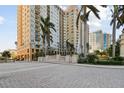 Elegant high-rise building with lush landscaping, a fountain, and a paved entrance at 750 N Tamiami Trl # 1203, Sarasota, FL 34236