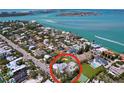 Aerial view of a charming coastal home with a tennis court, lush greenery, and breathtaking water views at 763 Siesta Dr, Sarasota, FL 34242