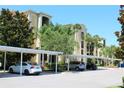 Covered parking in front of the condo building with beautiful landscaping and mature palm trees at 7803 Grand Estuary Trl # 205, Bradenton, FL 34212