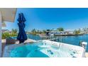 Waterfront patio with a luxurious hot tub, offering stunning views of the canal and boat dock at 10008 Spoonbill E Rd, Bradenton, FL 34209