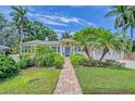 Charming single-story home featuring lush landscaping, a brick walkway, and a welcoming blue front door at 1960 Lincoln Dr, Sarasota, FL 34236