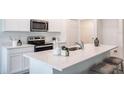 Bright kitchen featuring white cabinets, stainless steel appliances, a granite countertop island, and modern finishes at 21061 Delake Ave, Port Charlotte, FL 33954