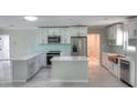 Bright modern kitchen boasts white cabinets, stainless steel appliances, a center island, and marble countertops at 306 Island Cir, Sarasota, FL 34242