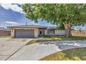 Attractive single-story home showcasing a stone facade, attached garage, and well-maintained lawn, shaded by a large, mature tree at 3136 Webber St, Sarasota, FL 34239