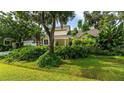 A yellow house surrounded by lush landscaping and mature trees, creating a private and serene setting at 4326 Brackenwood Ct, Sarasota, FL 34232
