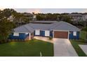 Stunning waterfront home featuring a blue exterior, metal roof, and well-manicured lawn with a private dock at 4517 Pinfish Ln, Palmetto, FL 34221