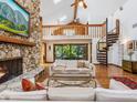 Spacious living room featuring a stone fireplace, a spiral staircase, vaulted ceilings, and large sliding glass doors at 4917 Hidden Oaks Trl, Sarasota, FL 34232