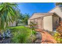 Landscaped front yard showcases a brick pathway and tropical plants leading to the side door at 4947 Greencroft Rd # 175, Sarasota, FL 34235