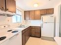 A cozy kitchen featuring wood cabinetry, a double basin sink beneath a window, and white appliances at 5901 Garden Ln # H23, Bradenton, FL 34207