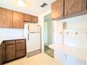 View of a kitchen with wood cabinets, white appliances, and a built-in wall desk with mushroom-themed tiling at 5901 Garden Ln # H23, Bradenton, FL 34207