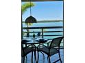 Charming balcony view with a dining table setup overlooking the serene waterfront and lush greenery beyond at 615 Dream Island Pl # 303, Longboat Key, FL 34228