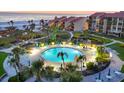 Aerial view of a large outdoor pool with lounge chairs, lush landscaping, and a spa overlooking the beach at 6236 Midnight Pass Rd # 300, Sarasota, FL 34242