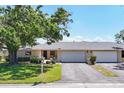 Inviting exterior of condo featuring an attached garage, well-maintained lawn, and large shade trees at 7069 W Country Club N Dr # 7069, Sarasota, FL 34243