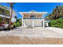 Charming stilted beach house with a spacious balcony, two-car garage, and tropical landscaping at 811 Jacaranda Rd, Anna Maria, FL 34216