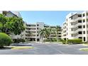 View of a condo building with palm trees and covered parking on a sunny day at 835 S Osprey Ave # 310, Sarasota, FL 34236