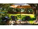 Relaxing backyard featuring a patio area with chairs, umbrella, grill, and lush green lawn at 1613 6Th W St, Palmetto, FL 34221