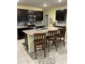 Modern kitchen with dark cabinets, granite countertops, stainless steel appliances, and a center island at 16919 Trite Bend St, Wimauma, FL 33598