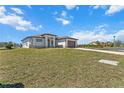 Modern, light gray home with a brown roof and a beautifully paved driveway and front lawn at 197 Rotonda Cir, Rotonda West, FL 33947