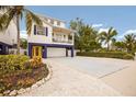 Charming stilted home featuring blue accents, a metal roof, a well-manicured lawn, and a spacious driveway at 318 64Th St, Holmes Beach, FL 34217