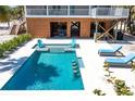 Gorgeous pool area with light-colored patio, blue lounge chairs, and a peek into the covered area under the house at 32 Palm Dr, Placida, FL 33946