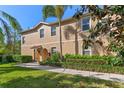 Inviting two-story tan home with a well-manicured lawn, lush landscaping, and a welcoming covered entryway at 3671 Parkridge Cir # 8-201, Sarasota, FL 34243