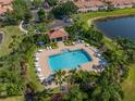 Aerial view of a resort-style pool surrounded by lush landscaping, loungers, and shade structures at 3671 Parkridge Cir # 8-201, Sarasota, FL 34243
