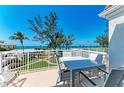 Relaxing balcony view featuring white patio furniture, tropical landscaping, and serene ocean backdrop at 5055 Gulf Of Mexico Dr # 232, Longboat Key, FL 34228