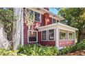 A red home with traditional architecture and a sunroom is surrounded by lush green vegetation at 624 19Th W St, Bradenton, FL 34205
