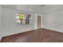 Bright living room with white walls, wood floors, and natural light from a large window at 9430 Glen Moor Ln, Port Richey, FL 34668