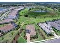 Panoramic view showcasing a home with a tile roof, paved driveway, and extensive landscaping near a large pond at 17114 Verona Pl, Lakewood Ranch, FL 34202
