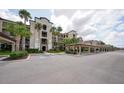 Exterior shot of the condo building showing a covered parking area, mature palm trees, and landscaping at 17118 Vardon Ter # 307, Bradenton, FL 34211
