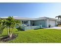Charming teal home boasts lush green lawn, mature palm trees, and tiled roof at 217 Giotto Dr, Nokomis, FL 34275