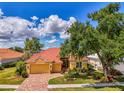 Well-maintained home with a red tile roof, a two-car garage, and vibrant, mature landscaping at 410 Wellington, Venice, FL 34292