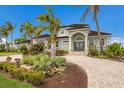 Elegant two-story home with lush landscaping, mature palms, a circular brick driveway, and a double-door entry at 4355 Pompano Ln, Palmetto, FL 34221