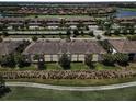 Aerial view of condo complex with tile roofs near a pond, golf course, and suburban homes in the background at 5528 Palmer Cir # 204, Lakewood Ranch, FL 34211