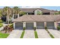 Exterior of a condominium featuring a tile roof, three garages, a brick driveway, and manicured landscaping at 5528 Palmer Cir # 204, Lakewood Ranch, FL 34211