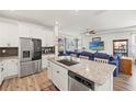 Open concept kitchen with stainless steel appliances and an eat-in island flowing into the living area at 7322 34Th E Ct, Sarasota, FL 34243