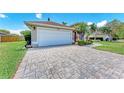 Paver driveway leads to a two-car garage of a one-story home with attractive landscaping at 7814 48Th E Ave, Bradenton, FL 34203