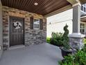 Inviting front porch with stone accents, decorative wreath, and lush greenery at 8346 Abalone Loop, Parrish, FL 34219