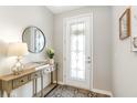 Elegant foyer featuring a decorative glass door, stylish console table with a lamp, and a round mirror, creating a welcoming entrance at 9095 Rally Spring Loop, Wesley Chapel, FL 33545