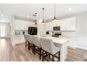 Bright kitchen with modern white cabinetry, stainless appliances, an island with bar stool seating and stylish pendant lighting at 9095 Rally Spring Loop, Wesley Chapel, FL 33545